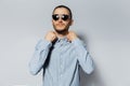 Studio portrait of young serious man wearing sunglasses and blue shirt on white background Royalty Free Stock Photo