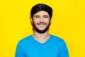 Studio portrait of young smiling guy wearing blue shirt on background of yellow color. Royalty Free Stock Photo