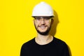 Studio portrait of young smiling man architect, builder engineer, wearing black sweater, white construction safety helmet and glas