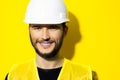 Studio portrait of young smiling man architect, builder engineer, wearing construction safety hard helmet and reflective jacket.