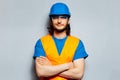 Studio portrait of young smiling man with crossed arms, construction worker engineer wearing safety equipment, hard hat, goggles. Royalty Free Stock Photo