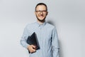 Studio portrait of young smiling man with laptop in hand, on white background. Wearing blue shirt and eyeglasses. Royalty Free Stock Photo