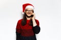 Studio portrait of young smiling man in red sweater, wearing Santa Claus hat and eyeglasses, talking on smartphone. Isolated on Royalty Free Stock Photo