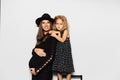 Studio portrait of young smiling pregnant woman with her daughter on white background. Wearing hat, dressed in black. Royalty Free Stock Photo