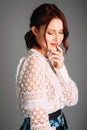 Studio portrait of young beautiful ginger woman in white lace blouse on grey background. Royalty Free Stock Photo