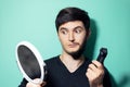 Studio portrait of young surprised man with half shaved face, looking in mirror holding electric shaver trimmer on background. Royalty Free Stock Photo