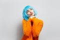 Studio portrait of young sweet girl with blue hair thinking positive, looking up, blowing kisses against white background. Royalty Free Stock Photo