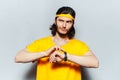 Studio portrait of young thoughtful and confident man in yellow shirt, using smartwatch on background of grey textured wall. Royalty Free Stock Photo