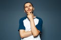 Studio portrait of young thoughtful man looking up with hand under chin on blue background Royalty Free Stock Photo