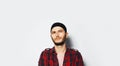 Studio portrait of young thoughtful man looking up, wearing red shirt and black band on head, on white background Royalty Free Stock Photo