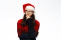 Studio portrait of young thoughtful man in red sweater, looking away, wearing Santa Claus hat and eyeglasses. Isolated on white Royalty Free Stock Photo