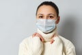 Studio portrait of young woman wearing a face mask, looking at camera, close up, isolated on gray background. Flu epidemic, dust