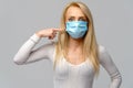 Studio portrait of young woman wearing a face protective mask isolated on gray background - flu virus epidemic