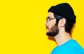 Studio profile portrait of young hipster guy looking on empty background of yellow color with copy space. Wearing blue shirt. Royalty Free Stock Photo