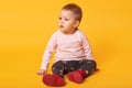 Studio shot of adorable little baby girl sitting on floor, isolated on yellow background, lovely baby portrait wearing casual Royalty Free Stock Photo