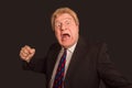 Studio shot of angry senior businessman with fist raise against dark background Royalty Free Stock Photo