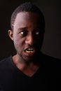 Studio shot of angry young black African man screaming in dark r Royalty Free Stock Photo