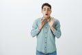 Studio shot of anxious troubled miserable guy in casual outfit, raising palms and staring with fright at camera, being