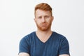 Studio shot of attractive adult caucasian redhead guy with bristle, pursing lips and frowning being troubled to answer