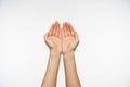 Studio shot of attractive fair-skinned hands of young female forming together, going to pick up water in folded palms. Body