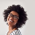 As happy and carefree as can be. Studio shot of an attractive and happy young woman wearing glasses against a gray Royalty Free Stock Photo