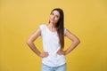 Studio shot of attractive self confident young female in great mood feeling happy, holding hands on her slender waist