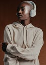 She knows how to style it up. Studio shot of an attractive young woman wearing headphones and posing against a brown Royalty Free Stock Photo