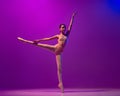 Studio shot of beautiful school age girl, ballet dancer dancing  on purple background in neon light. Art, grace Royalty Free Stock Photo