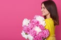 Studio shot of beautiful woman holding pink and white peony flowers and smiling while looking aside, happy model posing isolated Royalty Free Stock Photo