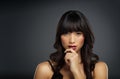 Shes irresistible isnt she. Studio shot of a beautiful young woman posing with her hand on her face against a dark