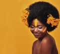 What a melanin gem. Studio shot of a beautiful young woman posing topless with sunflowers in her hair against a mustard Royalty Free Stock Photo