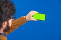 Studio shot from behind of a caucasian bearded brunet man in a brown sweater holding mockup green screen phone in his Royalty Free Stock Photo