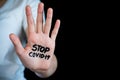 Close-up of open hand with Stop Covid-19 written on palm, with black background and copy space Royalty Free Stock Photo