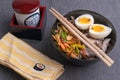 Studio shot of black bowl of ramen noodles with boiled eggs, veggies and turkey meet, ready to be poured with boiling