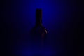 Studio shot of blue illuminated isolated dark black blurred red wine bottle silhouette focus on bottle neck Royalty Free Stock Photo