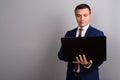 Businessman wearing suit while holding laptop against gray backg Royalty Free Stock Photo