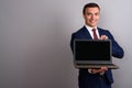 Businessman wearing suit while holding laptop against gray backg Royalty Free Stock Photo