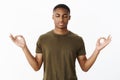 Studio shot of calm and peaceful young african american sportsman standing in lotus pose searching nirvana and patience