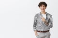 Studio shot of carefree happy and attractive hipser guy with dark curly har moustache and tattooed arm pointing at upper Royalty Free Stock Photo