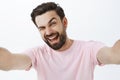 Studio shot of charismatic happy and enthusiastic handsome macho man with beard and dark hairstyle winking and smiling