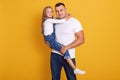Studio shot of charming kid girl with her father, handsome man holding child in hands, wearing casual clothing, posing isolated Royalty Free Stock Photo