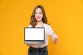 Studio shot of cheerful beautiful Asian woman in white t-shirt and holding laptop mockup.