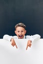 Studio shot of a cheerful Caucasian boy looking out from behind a banner Royalty Free Stock Photo