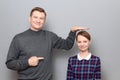 Tall man is showing height of short woman and pointing at her Royalty Free Stock Photo