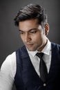 Studio shot of cheerful, young, handsome Indian male model in formal wear wearing white shirt, black tie, black coat against grey Royalty Free Stock Photo