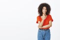 Studio shot of confident charming dark-skinned woman with afro hairstyle holding hand under chin and smiling broadly Royalty Free Stock Photo