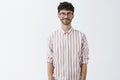 Studio shot of confident good-looking and stylish male model with beard in trendy glasses and striped shirt standing in Royalty Free Stock Photo