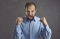 Angry frustrated aggressive man clenching fists and screaming isolated on gray background Royalty Free Stock Photo