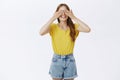 Studio shot of cute charismatic woman standing with anticipation over gray background closing eyes and holding palms on