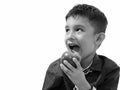 Studio shot of cute happy boy smiling and eating apple while thinking Royalty Free Stock Photo